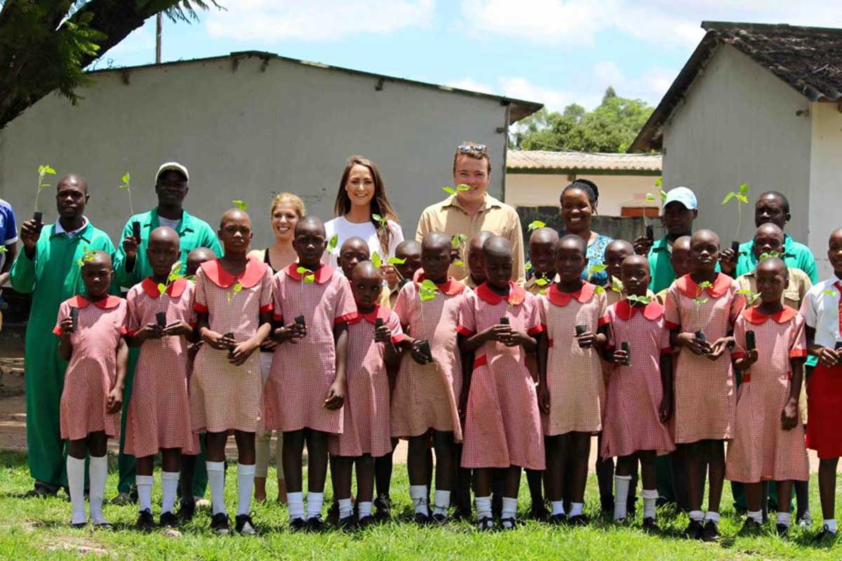 Line up of school children holding tree saplings
